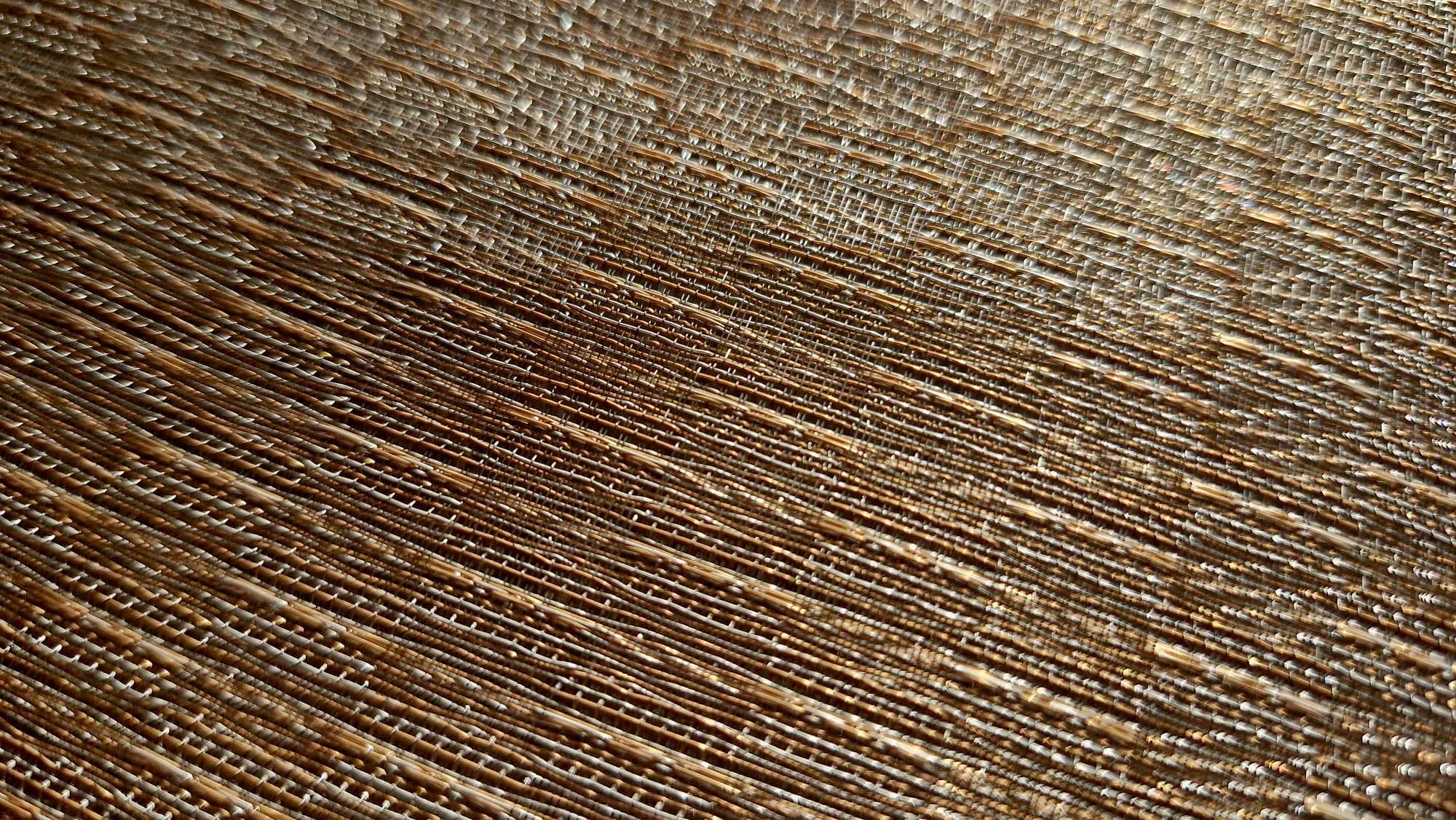 Macro detail of woven copper thread under raking light